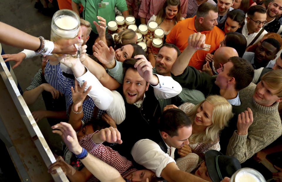 People reach out for a glass of beer during the opening of the 186th 'Oktoberfest' beer festival in Munich, Germany, Saturday, Sept. 21, 2019. (AP Photo/Matthias Schrader)