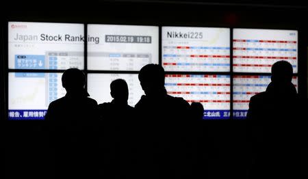 People walk past stock quotation boards outside a brokerage in Tokyo February 19, 2015. REUTERS/Toru Hanai