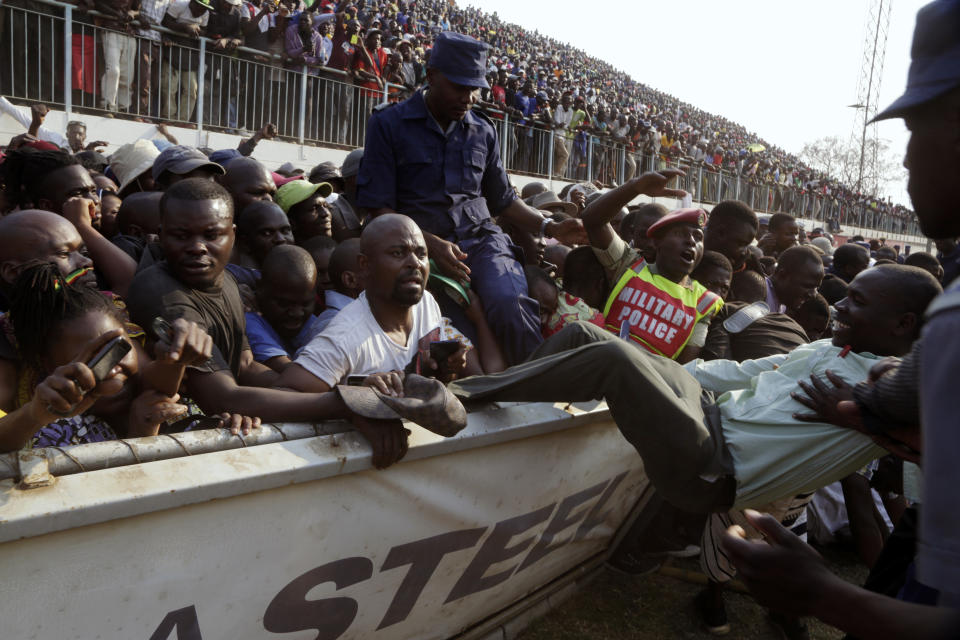 Mourners break through a barrier after the arrival of the coffin carrying former President Robert Mugabe at the Rufaro Stadium in Harare, Thursday, Sept. 12, 2019 where Mugabe will lie in state for a public viewing. Mugabe, the founder leader, made his final journey back to the country Wednesday amid continuing controversy over where he will be buried. (AP Photo/Themba Hadebe)