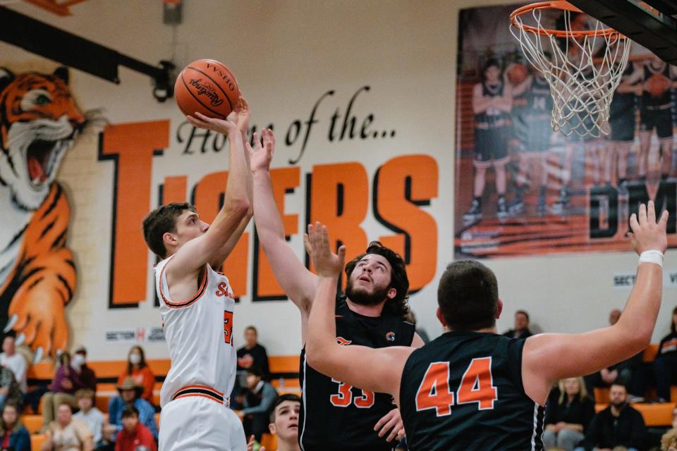Strasburg's Elijah Fierbaugh shoots over the attempted block by Newcomerstown's Gavin Prysi, middle, as Trenton Newkirk, right, looks for a possible rebound during their game in Strasburg, Tuesday, Nov. 30, 2021.