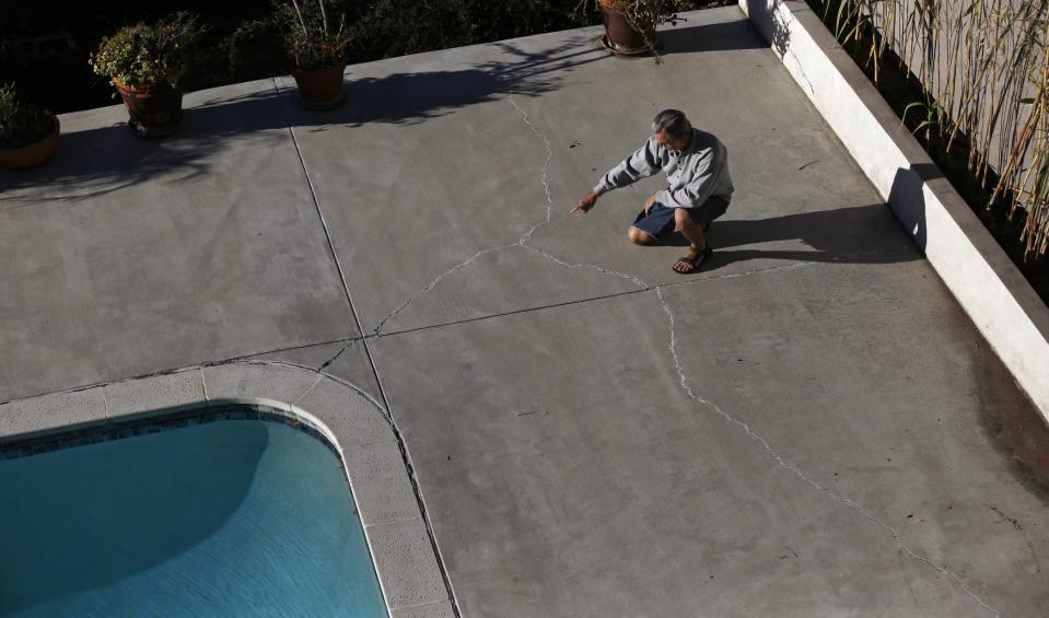 Homeowner Gary Gless points at cracks in cement in his backyard in Los Angeles