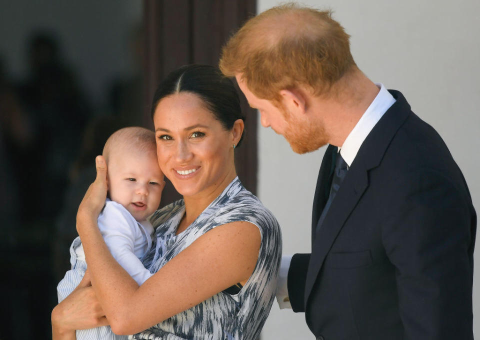 Meghan holding Archie as Harry looks on