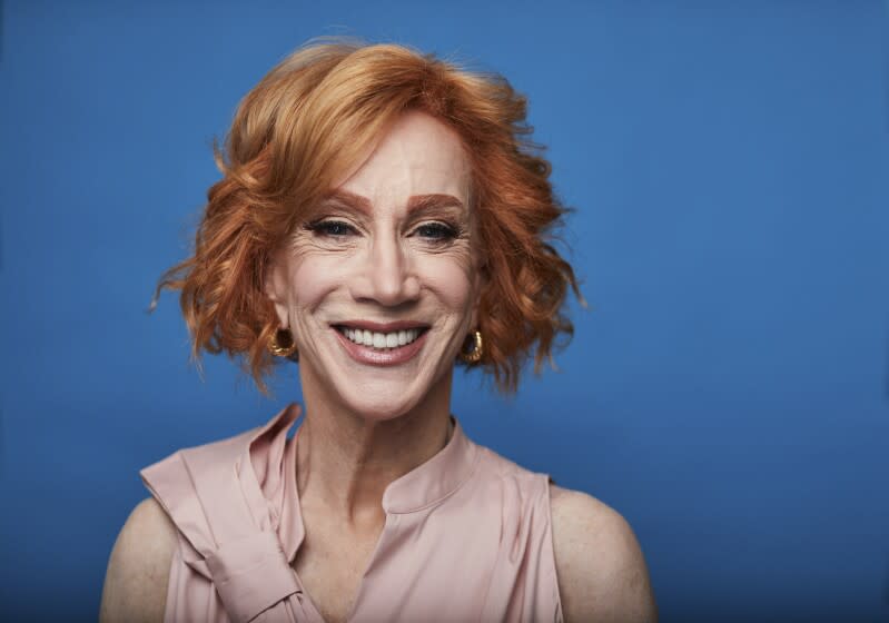 A woman with red hair smiling against a blue background