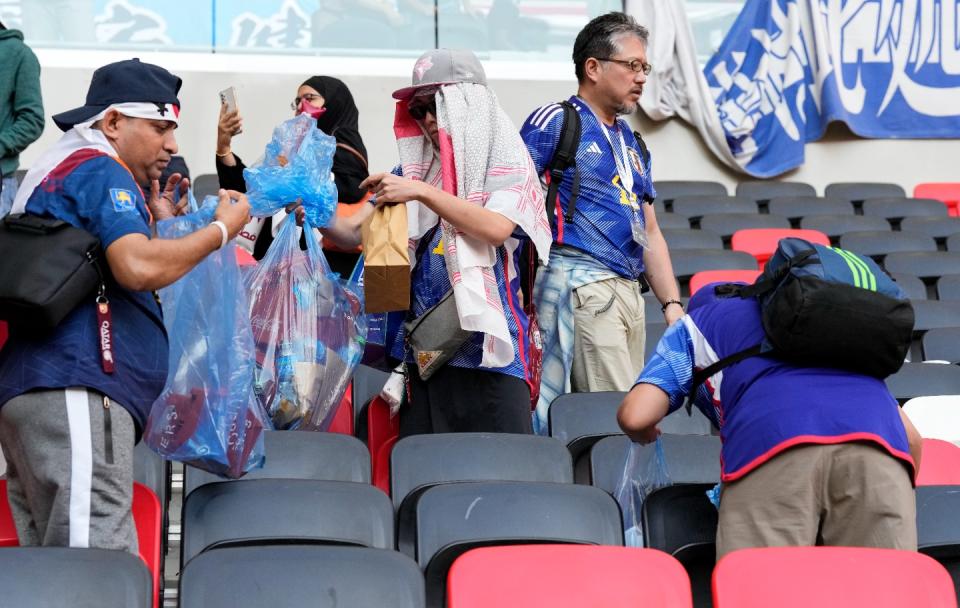 Japan's supporters clean their seats after losing the World Cup, group E football match between Japan and Costa Rica, at the Ahmad Bin Ali Stadium in Al Rayyan , Qatar, Sunday, Nov. 27, 2022. (AP Photo/Eugene Hoshiko)