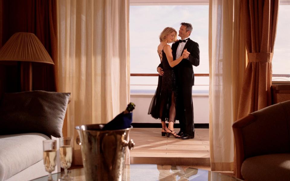 Elegant couple embracing in cruise ship cabin - Getty