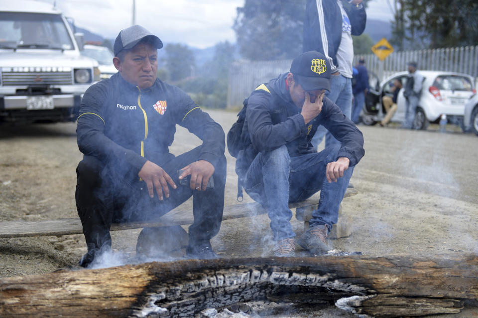 Dos hombres permanecen afuera de la morgue a la espera de noticias sobre las víctimas de la volcadura de un autobús que dejó al menos 12 muertos en Cuenca, Ecuador, el lunes 13 de agosto de 2018. (AP Foto/Javier Ramírez)