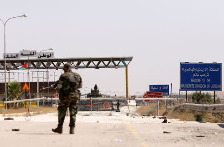 FILE PHOTO: A Syrian soldier walks as he holds his weapon at the Nasib border crossing with Jordan in Deraa, Syria July 7, 2018. REUTERS/ Omar Sanadiki/File Photo