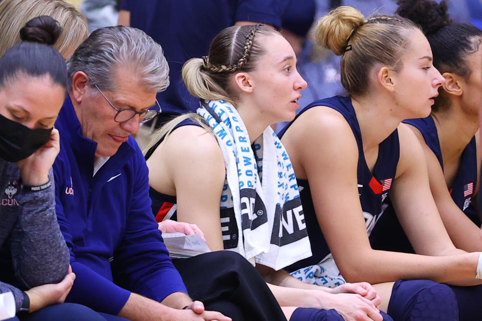 UConn guard Paige Bueckers on the bench next to head coach Geno Auriemma.