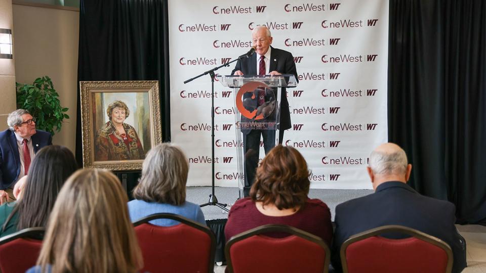 Stanley Schaeffer announces a $2.5 million gift to West Texas A&M University on Feb. 21 in memory of his late wife, Geneva (seen in portrait). Dyke Rogers, co-chair of the One West campaign leadership committee, looks on at left.