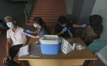 People receive a shot of the AstraZeneca's COVID-19 vaccine during a vaccination campaign at the Patriot Candrabhaga Stadium in Bekasi on the outskirts of Jakarta, Indonesia Friday, Nov. 26, 2021. Indonesia has significantly recovered from a mid-year spike in coronavirus cases and deaths that was one of the worst in the region, but with its vaccination drive stalling and holidays approaching, experts and officials warn the island nation could be set soon for another surge. (AP Photo/Achmad Ibrahim)