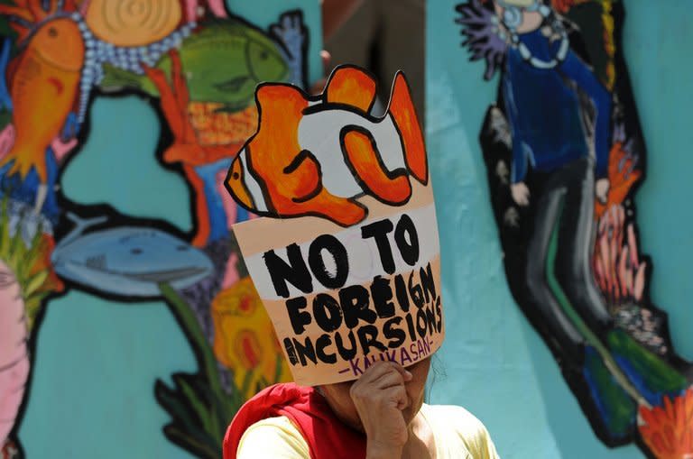 Protesters display placards during a rally in front of the Chinese consular office in Manila on April 11, 2013, against Chinese fishing Philippine waters