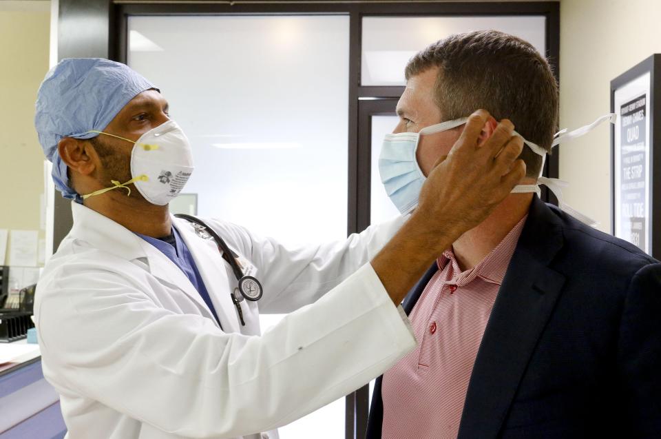 Dr. Ramesh Peramsetty wears a face mask with Mayor Walt Maddox at Peramsetty's First Care clinic in this March 31, 2020 photo.