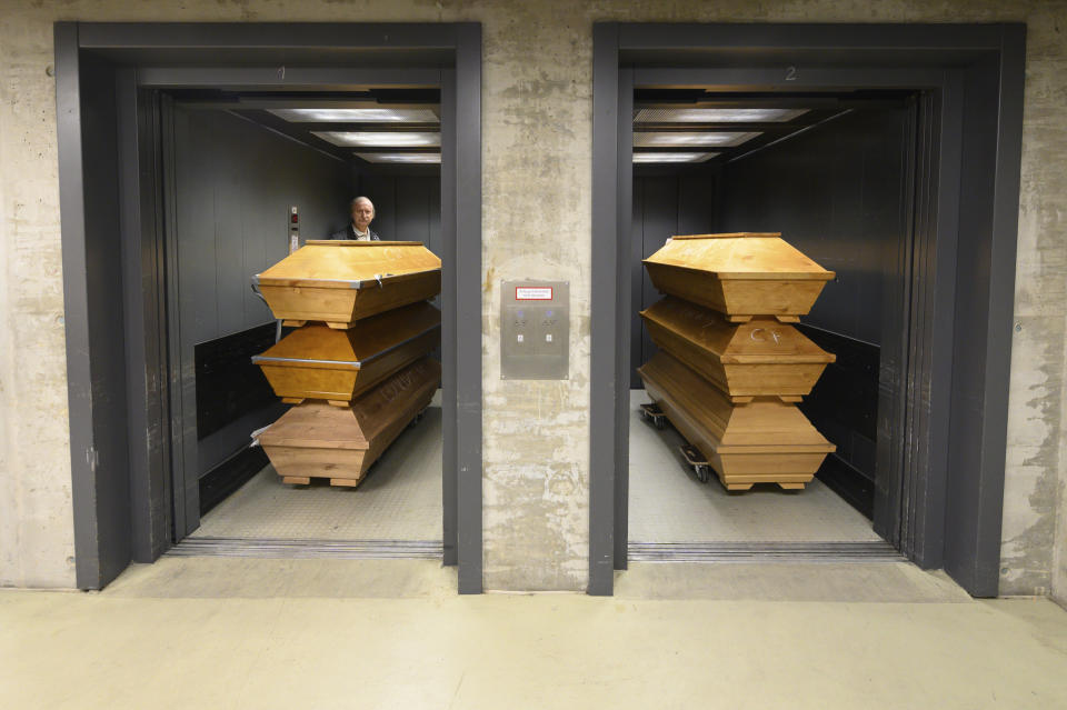 Claus-Dieter Turra, cremator, stands with coffins in an elevator with "Covid-19" chalked on coffins containing a deceased person who died with the coronavirus, with other coffins at the crematorium in Dresden, Germany, Tuesday Dec. 29, 2020. The crematorium has reached the limit of its capacity due to the high mortality in the Corona pandemic and is now dependent on help from other crematoria. (Sebastian Kahnert/dpa via AP)