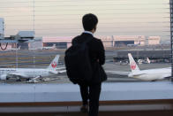 A man looks at Japan Airlines planes parked at Haneda international Airport in Tokyo, on Nov. 29, 2021. NHK TV said Wednesday, Dec. 1, that Japan will suspend new reservations on all incoming flights for a month to guard against new virus variant. (AP Photo/Koji Sasahara)