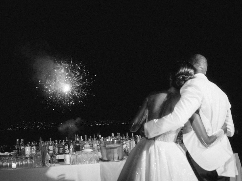 A bride and groom watch fireworks.