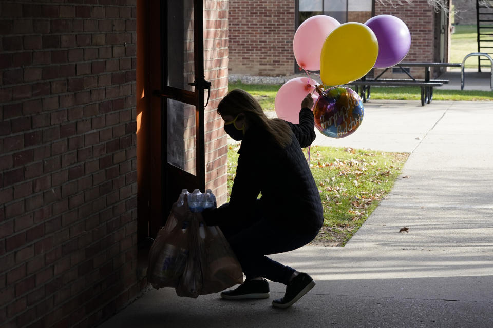 Erica Stowe delivers groceries and balloons to a student, Thursday, Nov. 19, 2020, in Ann Arbor, Mich. A group of parents has come together to help support University of Michigan students while they are sick or quarantining. The group of mostly moms was started and is organized by Sherry Levine of Rye Brook, New York, who's also a mother of a Michigan student. After she spread the word on parent pages on Facebook, local volunteers stepped up to help fulfill student requests by dropping off groceries or supplies. (AP Photo/Carlos Osorio)