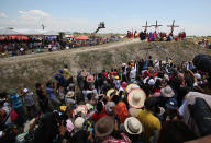 Spectators watch as Filipino devotee Ruben Enaje, center, stays nailed to a cross with two actors during a play to re-enact the crucifixion of Jesus Christ in San Pedro Cutud village, Pampanga province, northern Philippines on Friday, April 18, 2014. Church leaders and health officials have spoken against the practice which mixes Roman Catholic devotion with folk belief, but the annual rites continue to draw participants and huge crowds. (AP Photo/Aaron Favila)