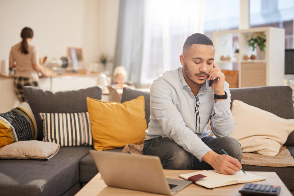 Portrait of modern mixed race man speaking by phone while working from home in cozy interior, copy space