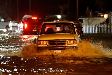 A motorist drives on a flooded street as water continues to rise after heavy rains overflowed nearby Coyote Creek in San Jose, California, U.S. February 21, 2017. Picture taken February 21, 2017. REUTERS/Stephen Lam