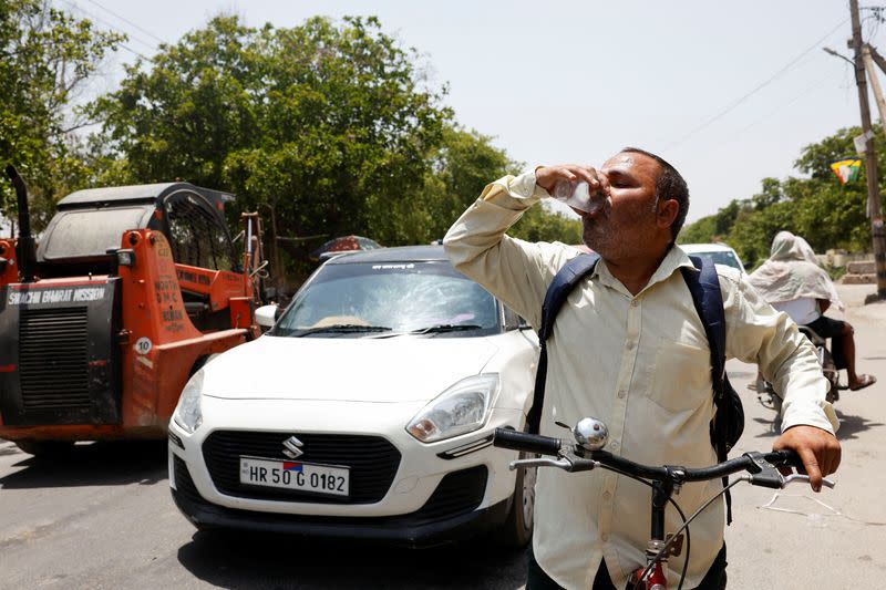 A man drinks a cooling drink offered by locals on a hot summer day during a heatwave in Narela