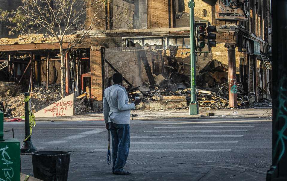 Un individuo observa la destrucción causada por manifestantes que protestan la muerte de George Floyd. Foto del 31 de mayo del 2020 tomada en la calle Lake Street, símbolo de la diversidad de Minneapolis. (AP Photo/Bebeto Matthews)