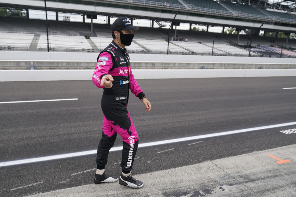 Helio Castroneves, of Brazil, walks down pit lane before a practice session for an IndyCar auto race at Indianapolis Motor Speedway, Friday, Aug. 13, 2021, in Indianapolis. (AP Photo/Darron Cummings)