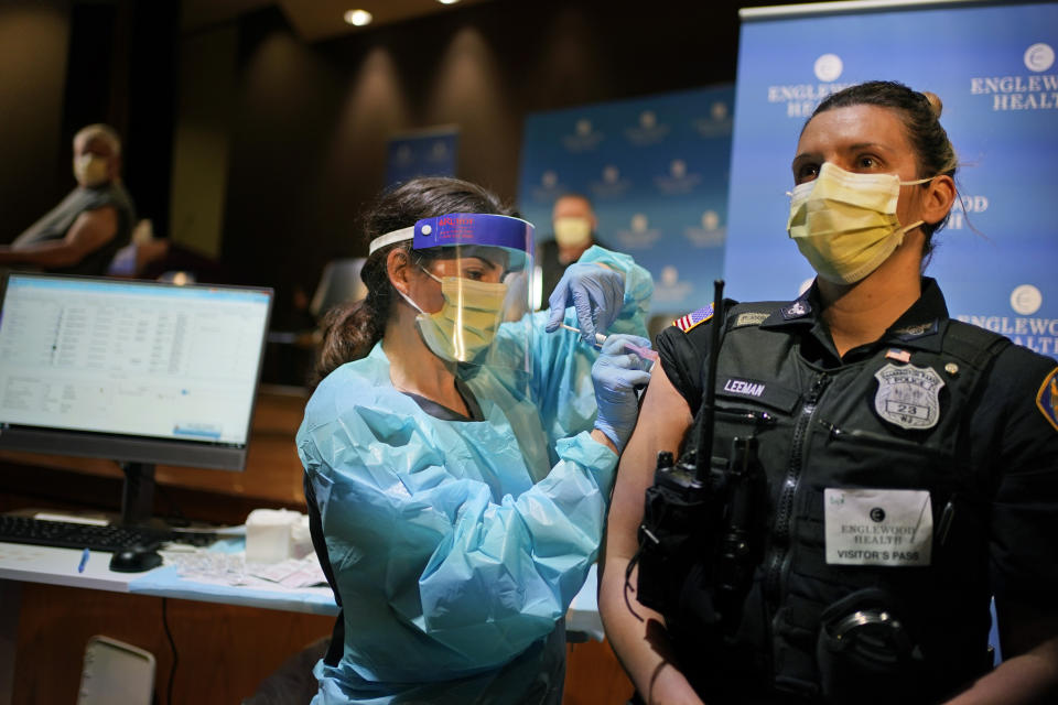 FILE - In this Jan. 14, 2021, file photo, police officer Jennifer Leeman is receives a COVID-19 vaccine at Englewood Health in Englewood, N.J. The resurgence of COVID-19 this summer and the national debate over vaccine requirements have created a fraught situation for the nation's first responders, who are dying in larger numbers but pushing back against mandates. (AP Photo/Seth Wenig, File)