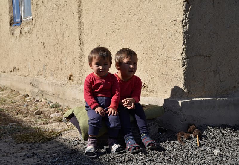 Ademi and Alina, granddaughters of pensioner Rakya Kudaiberdiyeva, sit outside the family's rented house in Bishkek