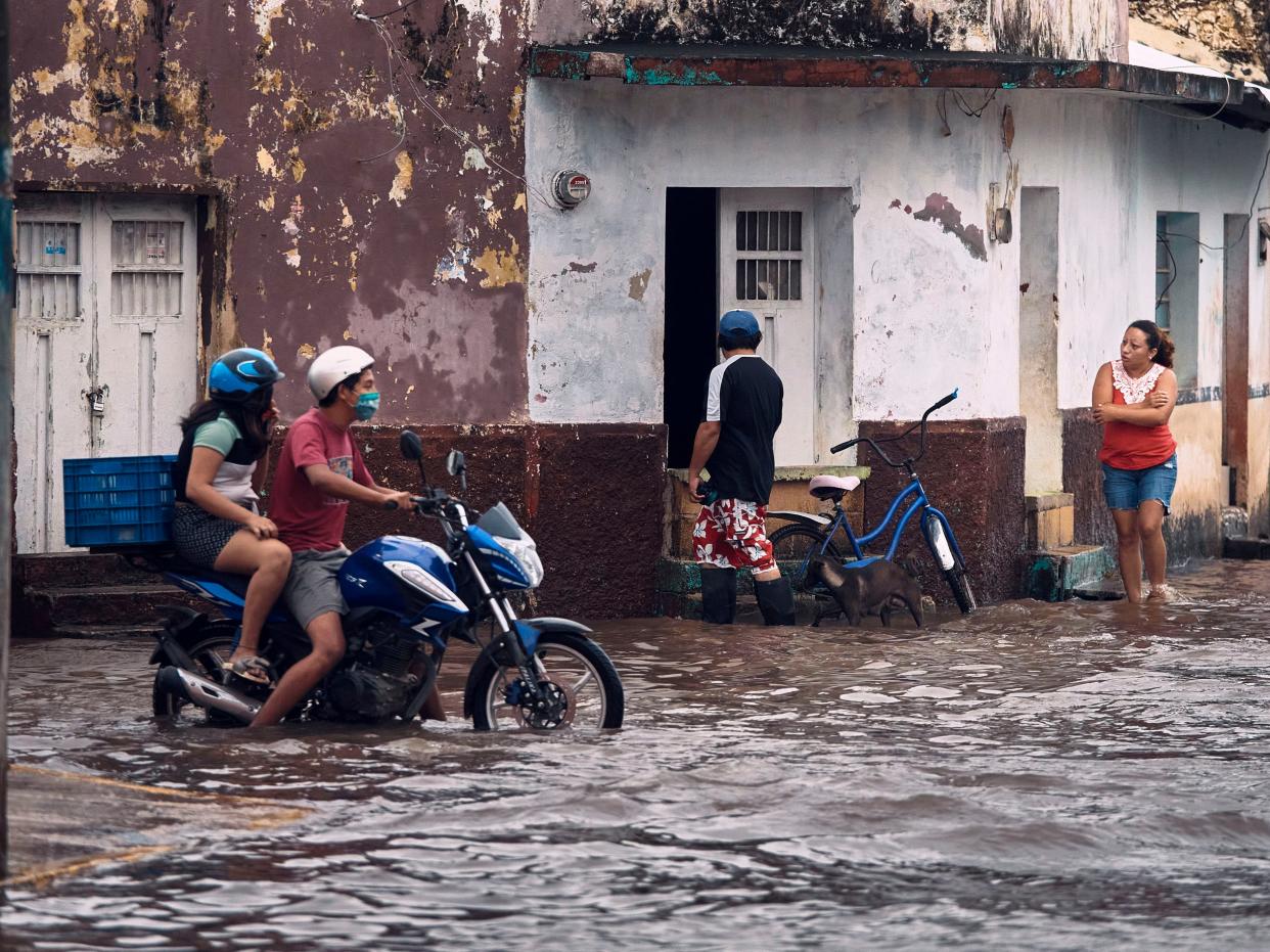 A couple rides a motorcycle along a flooded street after the passing of Hurricane Delta in Tizimin, Mexico, Wednesday, October 7, 2020 (AP)