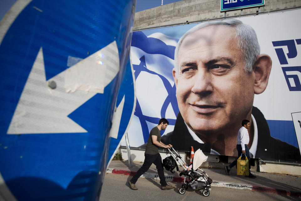 FILE - In this April 7, 2019 file photo, a man walks by an election campaign billboard showing Israel's Prime Minister Benjamin Netanyahu, the Likud party leader, in Tel Aviv, Israel. As Netanyahu becomes Israel’s longest-serving prime minister, he is solidifying his place as the country’s greatest political survivor and the most dominant force in Israeli politics in his generation. (AP Photo/Oded Balilty, File)