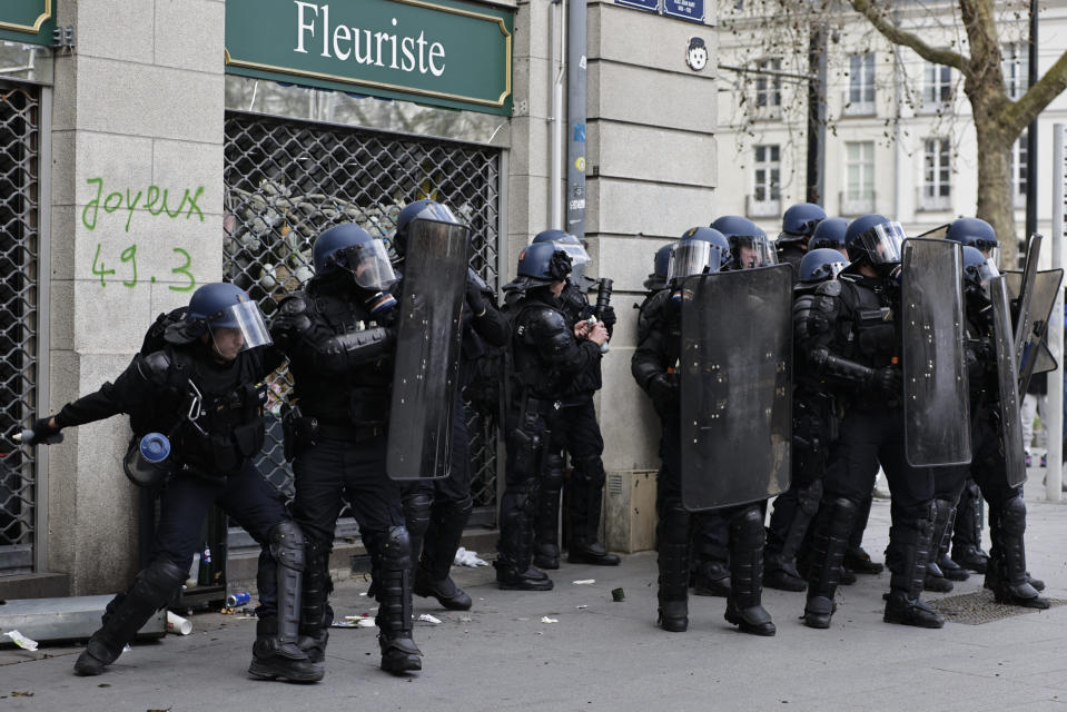 A police officer throws a grenade during a demonstration in Nantes, western France, Saturday, March 18, 2023. A spattering of protests are planned to continue in France over the weekend against President Emmanuel Macron's controversial pension reform. (AP Photo/Jeremias Gonzalez)