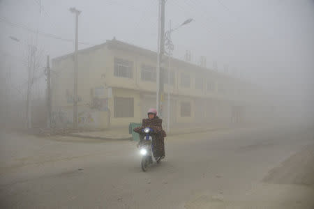 A cyclist rides along a street in heavy smog during a polluted day in Liaocheng, Shandong province, December 20, 2016. REUTERS/Stringer