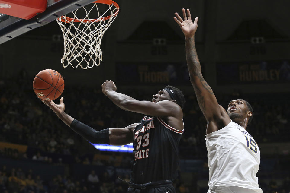 Oklahoma State forward Moussa Cisse (33) shoots while defended by West Virginia forward Jimmy Bell Jr. (15) during the first half of an NCAA college basketball game on Monday, Feb. 20, 2023, in Morgantown, W.Va. (AP Photo/Kathleen Batten)