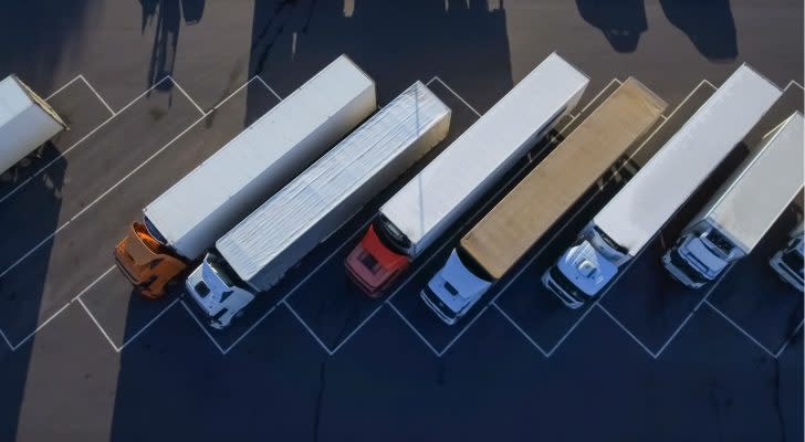 trucking stocks Aerial Top View of White Semi Truck with Cargo Trailer Parking with Other Trucks on Special Parking Lot.