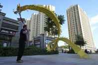 A resident wields a cloth dragon outside the Evergrande Yujing Bay residential complex in Beijing, China, Tuesday, Sept. 21, 2021. Global investors are watching nervously as one of China's biggest real estate developers struggles to avoid defaulting on tens of billions of dollars of debt, fueling fears of possible wider shock waves for the financial system. (AP Photo/Ng Han Guan)