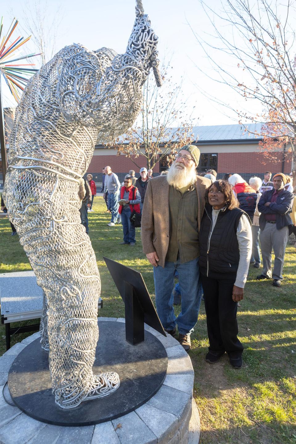 Renee Powell, daughter of Clearview Golf founder William J. Powell and the statue's artist Patrick Buckhohr, look over the final product during a dedication ceremony at the Minerva Public Library.