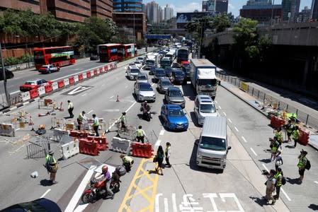 Workers remove barricades that were placed by protesters to block the road, at the Cross-Harbour Tunnel in Hong Kong