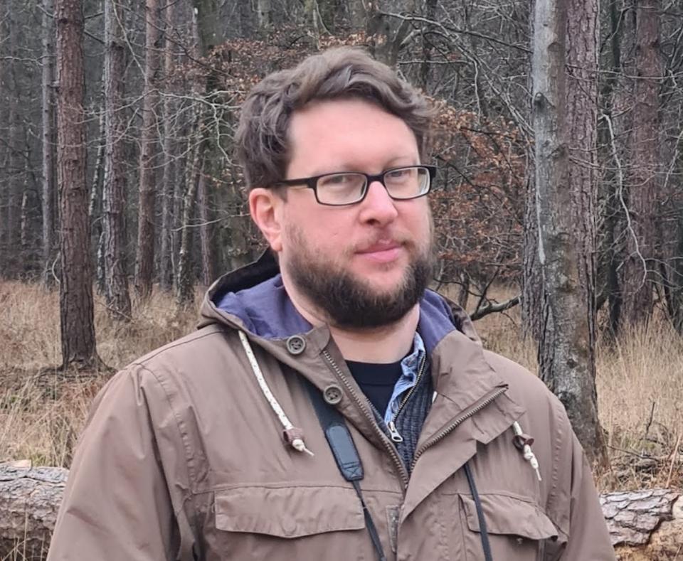 a man wearing glasses in a forest