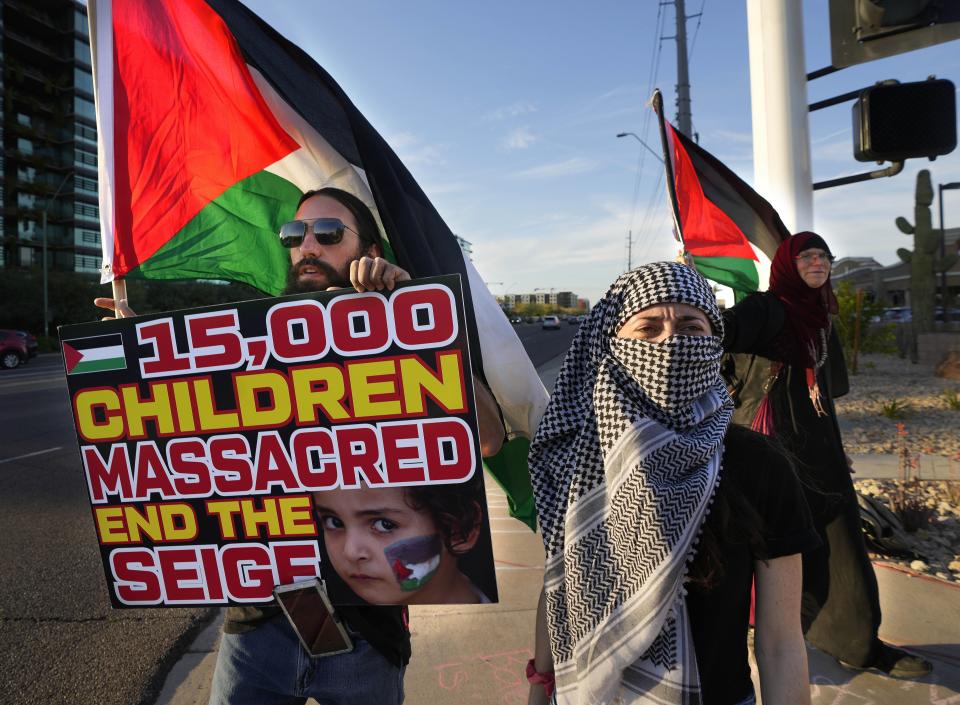 Rumsey Salman holds a Palestinian flag and a sign with Lynndsie as the group chants during a Free Palestine protest at the corner of Scottsdale Road and Greenway-Hayden Loop on March 22, 2024.