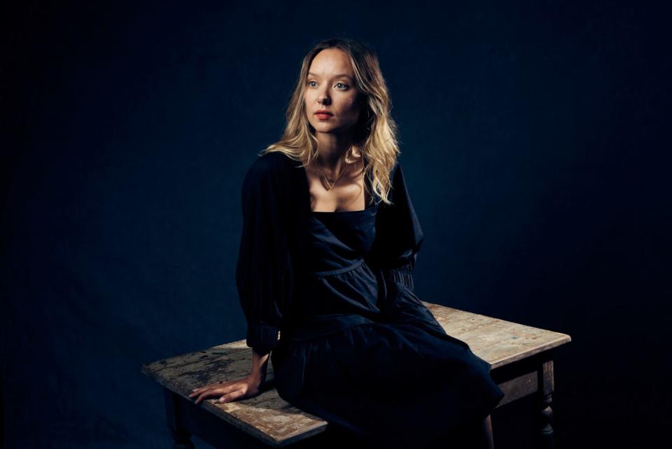 A woman sits on a table and looks to the side.