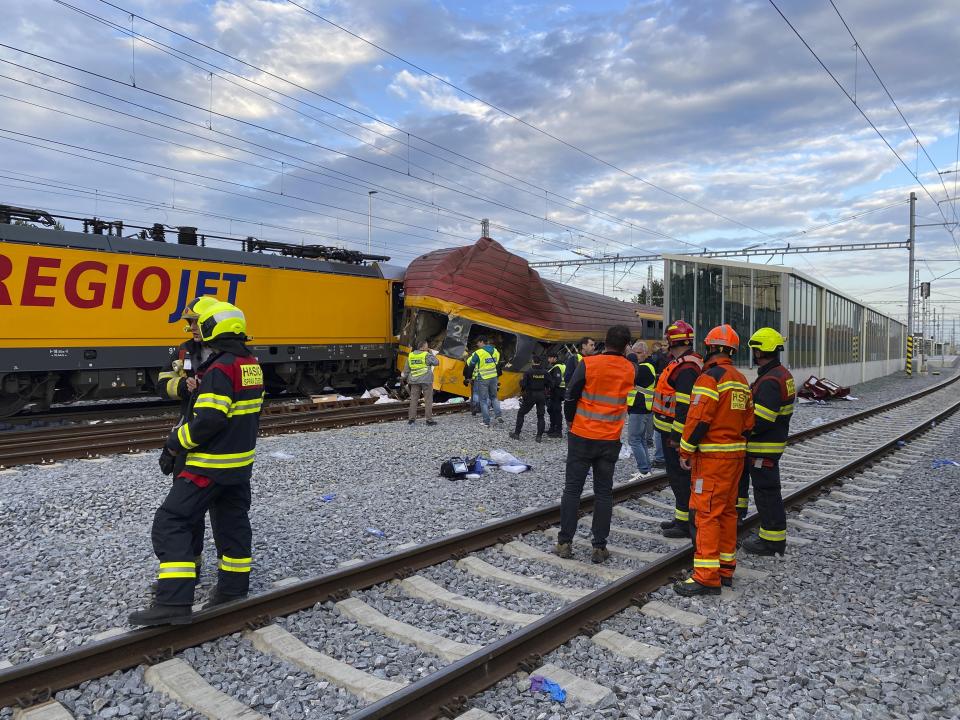 Firefighters stand by two trains that collided in Pardubice, Czech Republic Thursday, June 6, 2024. A passenger train collided head-on with a freight train in the Czech Republic, killing and injuring some people, officials said early Thursday. (AP Photo/Stanislav Hodina)