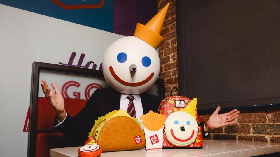 Jack Box character from Jack in the Box sits at a fast food table with Loungefly accessories in front of him