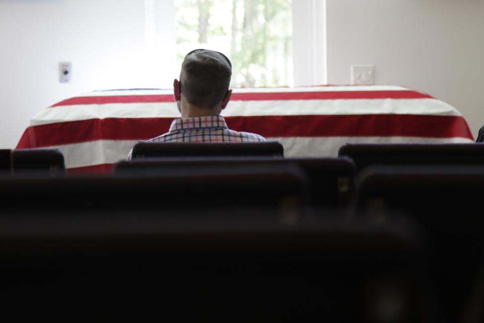 In this April 3, 2020, photo, Eric Coleman sits in front of his father's casket during his funeral, in Lexington, S.C. J. Robert Coleman's widow and three sons were spaced apart to follow social distancing guidelines during the coronavirus outbreak. (AP Photo/Sarah Blake Morgan)