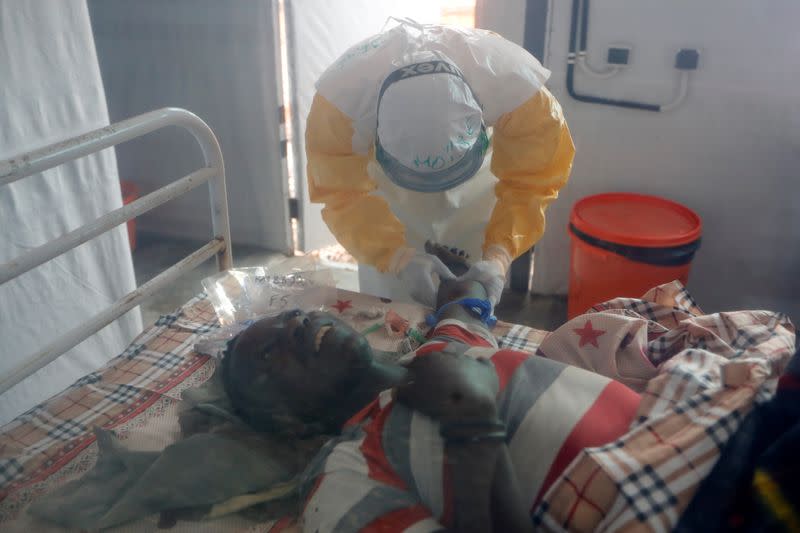 FILE PHOTO: Moise Vaghemi, an Ebola survivor who works as a nurse, tends to a patient who is suspected to be suffering from Ebola at an Ebola treatment centre (ETC) in Katwa