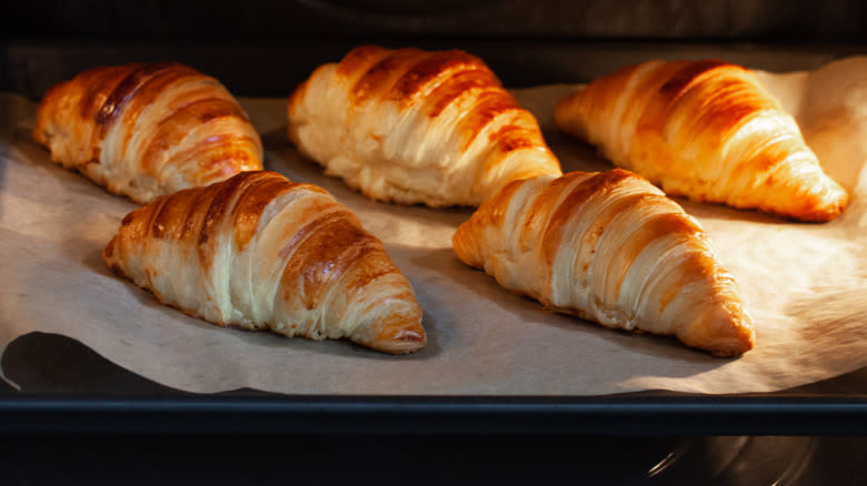 Homemade croissants reheating on a sheet in the oven