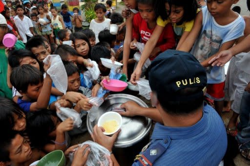 Children queue for rice porridge at a the local government-run feeding centre in the Baseco slum area in Manila. An average of five cups of steamed rice is cooked daily for every Filipino but nine grammes (three tablespoons) of this is wasted