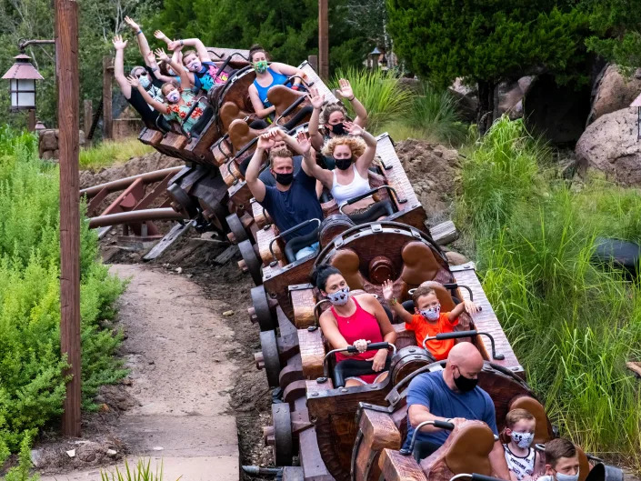 Guests with their hands up in the air on a wooden rollercoaster.