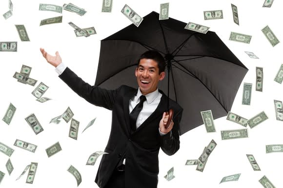 Money raining down on business man with umbrella