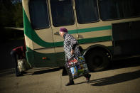 A woman, fleeing from an area near the front line in Donetsk, carries her belongings as she boards a bus in Kurakhove, eastern Ukraine, Monday, May 23, 2022. In the Donbas region, people continue to flee from towns and villages coming under heavy bombardment. (AP Photo/Francisco Seco)