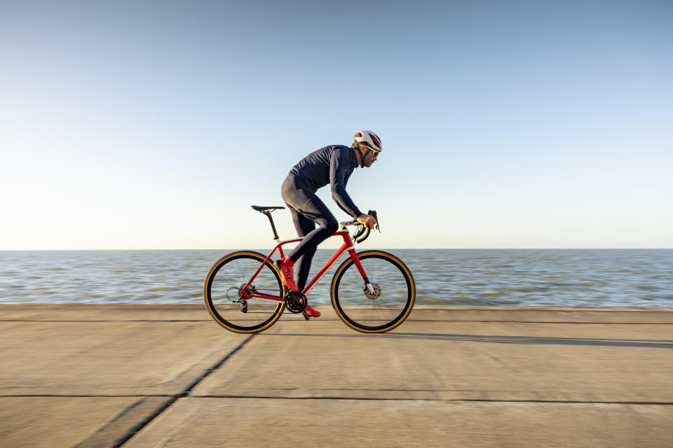 Mature cyclist riding bicycle on coastal path, Kent, United Kingdom
